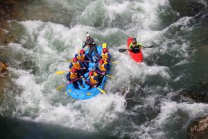 Family enjoying adventure tourism in a rafting activity in a river of Huesca, in the Pyrenees. One of the reasons to visit Graus